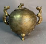 An etched bronze Chinese incense burner with dragon handles on tripod feet.