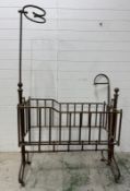 A Victorian brass rocking cradle on casters (185cm x 110cm x 56cm)