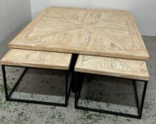 A contemporary square coffee table with parquet-style wooden top and black metal frame, together