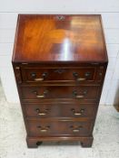 A mahogany bureau comprising of four graduated drawers with the fall opening to a green leather
