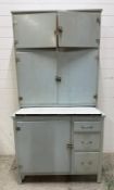 A vintage Hoosier style kitchen cabinet with pull out enamel work surface and two cupboard over