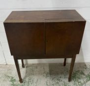 A mid-century two door haberdashery cabinet on legs. Doors opening to shelves and three central