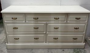 A contemporary white seven drawer chest of drawers (H71cm W142cm D47cm)