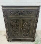 A Chinese hardwood heavily carved drinks cabinet with a hinged top opening for bottle storage -