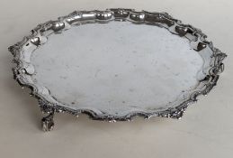 A QEII circular silver tray with an ornate pie-crust border on three scroll feet, hallmarked