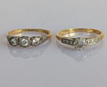 A three-stone diamond ring on a yellow gold and platinum setting and a single stone diamond ring