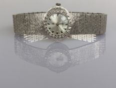 A mid-century GHC ladies manual wristwatch with baton markers, diamond bezel, case stamped 750
