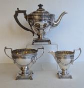 An Edwardian Scottish silver three-piece tea set, each decorated with lion masks and swags on platfo