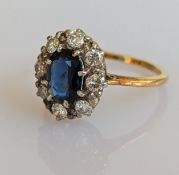 An oval sapphire and diamond cluster ring on a yellow gold claw setting