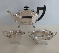An Art Deco silver three-piece tea service with faceted design, ebonized handle, on splayed feet