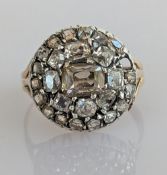 An Art Deco diamond cluster ring on a platinum and yellow gold setting, the central emerald-cut diam