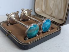 A pair of cased Edwardian silver knife rests with turquoise decoration, each 9 cm, 105g