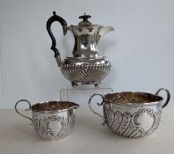 An Edwardian silver hot water pot with ebonized knop and handle, half-fluted design on ball feet