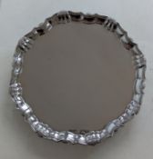 A George II silver salver with pie-crust border and scallop decoration raised on four hoof feet