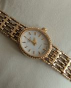 A cased ladies Rotary gold dress watch with oval white dial, baton markers on a 9ct yellow gold