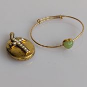 An adjustable yellow gold bangle with mounted jade decoration and an oval yellow gold locket 