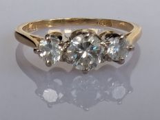 A three-stone graduated diamond ring on a yellow gold claw setting, the central round brilliant-cut