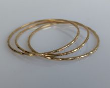 Three matching yellow gold bangles with carved decoration, each stamped 10k, 65mm, 22.2g (3)
