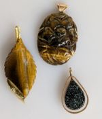 A tiger eye pendant shaped as a leaf, 72mm, (repaired) with 18ct yellow gold trim; another tiger eye