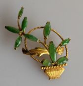 A jade and yellow gold brooch is the form of a floral spray and basket, stamped 14k, 5.1g