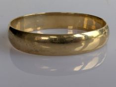 A yellow gold hinged bangle of plain form, 65mm, stamped 9ct, 17.2g