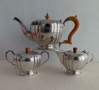 An Art Deco three-piece silver tea service with bakelite handles, fluted decoration, each raised on 