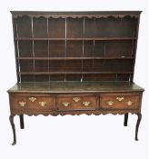 A George III Shropshire oak dresser, with moulded serpentine cornice above three shelves, over three