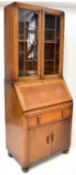 A 1930s oak bureau bookcase, the leaded glazed top over a base with slope, single drawer and pair of