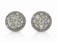 A central round brilliant cut diamond is surrounded by a halo of eight round brilliant cut diamonds.