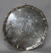 Silber. Flache runde Servierplatte mit flachem gewelltem Rand auf drei kleinen Füßchen. Im Spiegel