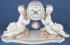 Kaminuhr "Uhr von zwei Putten getragen". Meissen nach 1934. Porzellan, korallenrot bemalt und gold 