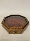 AN OCTAGONAL INLAID WOODEN DISPLAY CASE WITH A GLASS HINGED LID