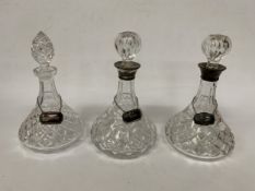THREE VINTAGE CUT GLASS DECANTERS WITH HALLMARKED SILVER LABELS AND HALLMARKED SILVER RIMS TO TWO OF