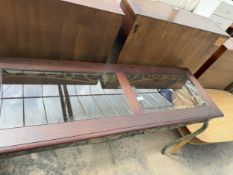 A HARDWOOD SIDE TABLE WITH INSET GLASS TOP ON SHAPED METALWARE LEGS AND FRIEZE, 52" WIDE