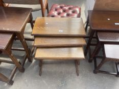 AN OAK NEST OF THREE TABLES WITH PEDESTAL TRESTLE STYLE SUPPORTS