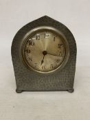 AN ARTS AND CRAFTS HAMMERED PEWTER CLOCK