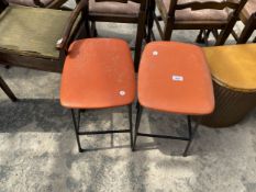 A PAIR OF STOOLS ON TUBULAR FRAMES WITH ORANGE SEATS