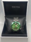 A SEIKO 5 SPORTS AUTOMATIC WRISTWATCH WITH GREEN DIAL, MATCHING BEZEL AND STAINLESS STEEL STRAP IN A