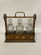 A VINTAGE OAK TANTALUS WITH BRASS FITTINGS