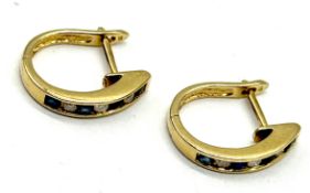 A pair of 14k gold earrings channel set with diamonds and sapphires - total weight 3.44g