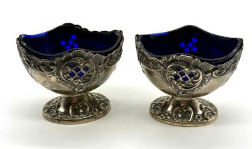 A pair of boat shaped silver salts on pedestal bases with blue glass liners (Birmingham 1904) -