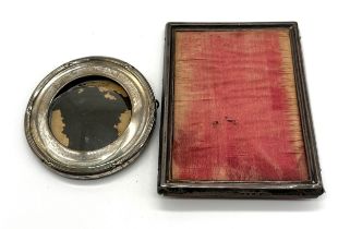 A rectangular silver photo frame along with a smaller round silver frame