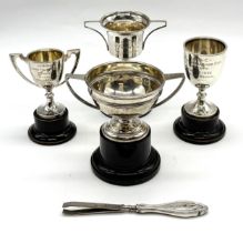 A collection of four small silver trophies along with a pair of silver handled tweezers - weight