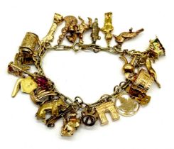 A 14ct gold charm bracelet with numerous 9ct and 14ct gold charms - total weight 51.90g