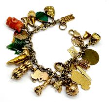 A 9ct gold charm bracelet with a mixture of 9, 14 and 18ct gold charms along with a carved coral