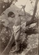 Gloeden, Wilhelm von: Young boy leaning on tree branch
