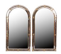 A pair of gilt metal framed arched wall mirrors,