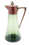 An Art Nouveau green glass claret jug of tapering form with embossed copper mounts and cover and