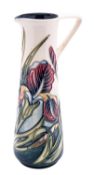 A Moorcroft pottery jug of tapering form with angular handle tube lined in the Iris pattern after a
