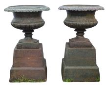 A pair of cast iron garden urns on plinths, 20th century; of Campana form,